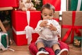 Adorable hispanic toddler hugging teddy bear sitting on floor by christmas gifts at home Royalty Free Stock Photo