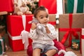 Adorable hispanic toddler hugging teddy bear sitting on floor by christmas gifts at home Royalty Free Stock Photo