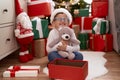 Adorable hispanic toddler hugging teddy bear sitting on floor by christmas gifts at home Royalty Free Stock Photo
