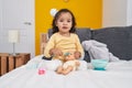 Adorable hispanic toddler playing with baby doll sitting on bed at bedroom Royalty Free Stock Photo