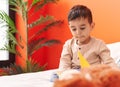 Adorable hispanic toddler reading book sitting on bed at bedroom Royalty Free Stock Photo