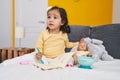 Adorable hispanic toddler sitting on bed reading book at bedroom Royalty Free Stock Photo