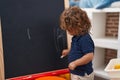 Adorable hispanic toddler student drawing on blackboard at kindergarten Royalty Free Stock Photo