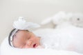 Adorable infant girl in white pajama sleeping on white cloth mattress. newborn baby having day nap in parents`s bed Royalty Free Stock Photo