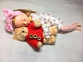 An adorable Japanese doll is sleeping with her teddy bear.