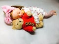 An adorable Japanese doll is sleeping with her teddy bear.