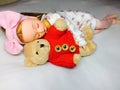 An adorable Japanese doll is sleeping with her teddy bear.