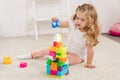 adorable kid with curly hair playing with colored plastic constructor on carpet