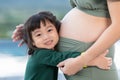 Adorable kid girl hugging pregnant mother belly to hearing sound of baby.Lovely little girl loving and waiting for newborn sister Royalty Free Stock Photo