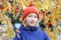 Cheerful kid girl smiling, the child is dressed in a funny knitted warm hat with ears, looks like a fox. Autumn, outdoors portrait Royalty Free Stock Photo