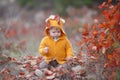 Little boy alone sits on dry grass in a beautiful autumn park on a background of red foliage Royalty Free Stock Photo