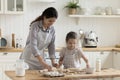 Adorable kid helping happy mom to bake, preparing homemade pies, Royalty Free Stock Photo