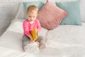 adorable kid in pink shirt holding book on bed