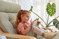 Adorable kid playing videogame on smartphone sitting on armchair Royalty Free Stock Photo