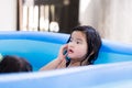 Adorable kids girl took a dip in the blue rubber pool with peace of mind. Asian child play with water in summer. Royalty Free Stock Photo