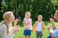 adorable kids holding hands and looking at parents blowing soap bubbles Royalty Free Stock Photo