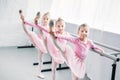 adorable kids in pink tutu skirts practicing ballet and looking at camera