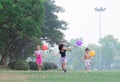 Adorable kids play together with cheerful and very enjoyable, children hold colorful balloons in hand and competitive run in green Royalty Free Stock Photo