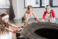 Adorable kids in sportswear training with tire at fitness studio Royalty Free Stock Photo