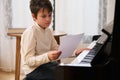 Adorable preteen child boy, pianist musician touching piano keyboard, learning notes during music lesson at home