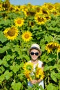 Adorable laughing blond boy in sun glasses and hat with sunflower on field outdoors Royalty Free Stock Photo