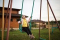 Adorable laughing little girl on swing in summer day. Happy children day concept. Kid playing outdoor on backyard Royalty Free Stock Photo