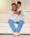 Adorable little african american boy hugging his father while relaxing on a sofa at home. Caring man with his loving son Royalty Free Stock Photo