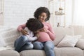 Adorable little african girl kissing and hugging her pregnant mom`s tummy Royalty Free Stock Photo