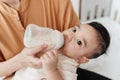 Adorable little Asian baby drinking milk from baby bottle. Mother holding adorable her son with milk feeding from milk bottle. Royalty Free Stock Photo