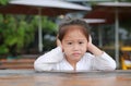 Adorable little Asian child girl expressed disappointment or displeasure on the wood table with looking camera