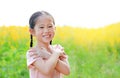 Adorable little Asian child girl feeling free with hand folded cross one`s arm in Sunhemp field with sunlight outdoor. Yellow Royalty Free Stock Photo