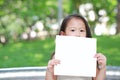 Adorable little Asian child girl holding up a blank white paper