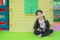 Adorable little Asian child girl listening music by headphone near toy playhouse in playground Royalty Free Stock Photo