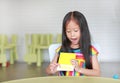 Adorable little Asian child girl is playing with educational colors flashcards while sitting at table in children room