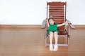 Adorable little Asian child girl relaxing on Thai wooden traditional chair Royalty Free Stock Photo