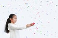 Adorable little Asian child girl shooting party popper confetti over white background with copy space