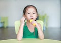 Adorable little Asian child girl sing a song by plastic microphone at the kid room Royalty Free Stock Photo