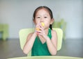 Adorable little Asian child girl sing a song by plastic microphone at the kid room Royalty Free Stock Photo