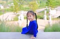 Adorable little Asian child girl sitting on stair in the garden with looking camera Royalty Free Stock Photo