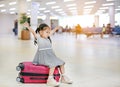 Adorable little asian girl at airport sitting on suitcase with open arm Royalty Free Stock Photo