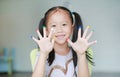 Adorable little Asian girl with colorful fingers painted in the children room