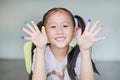 Adorable little Asian girl with colorful fingers painted in the children room