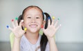 Adorable little Asian girl with colorful fingers painted in the children room