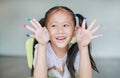 Adorable little Asian girl with colorful fingers painted in the children room