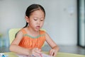 Adorable little Asian girl drawing and painting with water color on paper in children room Royalty Free Stock Photo