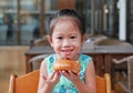 Adorable little Asian girl eating bread. Child having breakfast Royalty Free Stock Photo