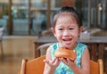 Adorable little Asian girl eating bread. Child having breakfast Royalty Free Stock Photo