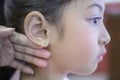 Adorable little Asian girl having ear piercing process.