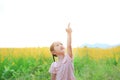 Adorable little Asian kid girl feeling free with pointing up in Sunhemp field. Yellow flowers background Royalty Free Stock Photo