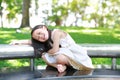 Adorable little Asian kid girl sitting on bench in sunny green park Royalty Free Stock Photo